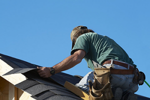 a handyman patches a roof leak with new shingles